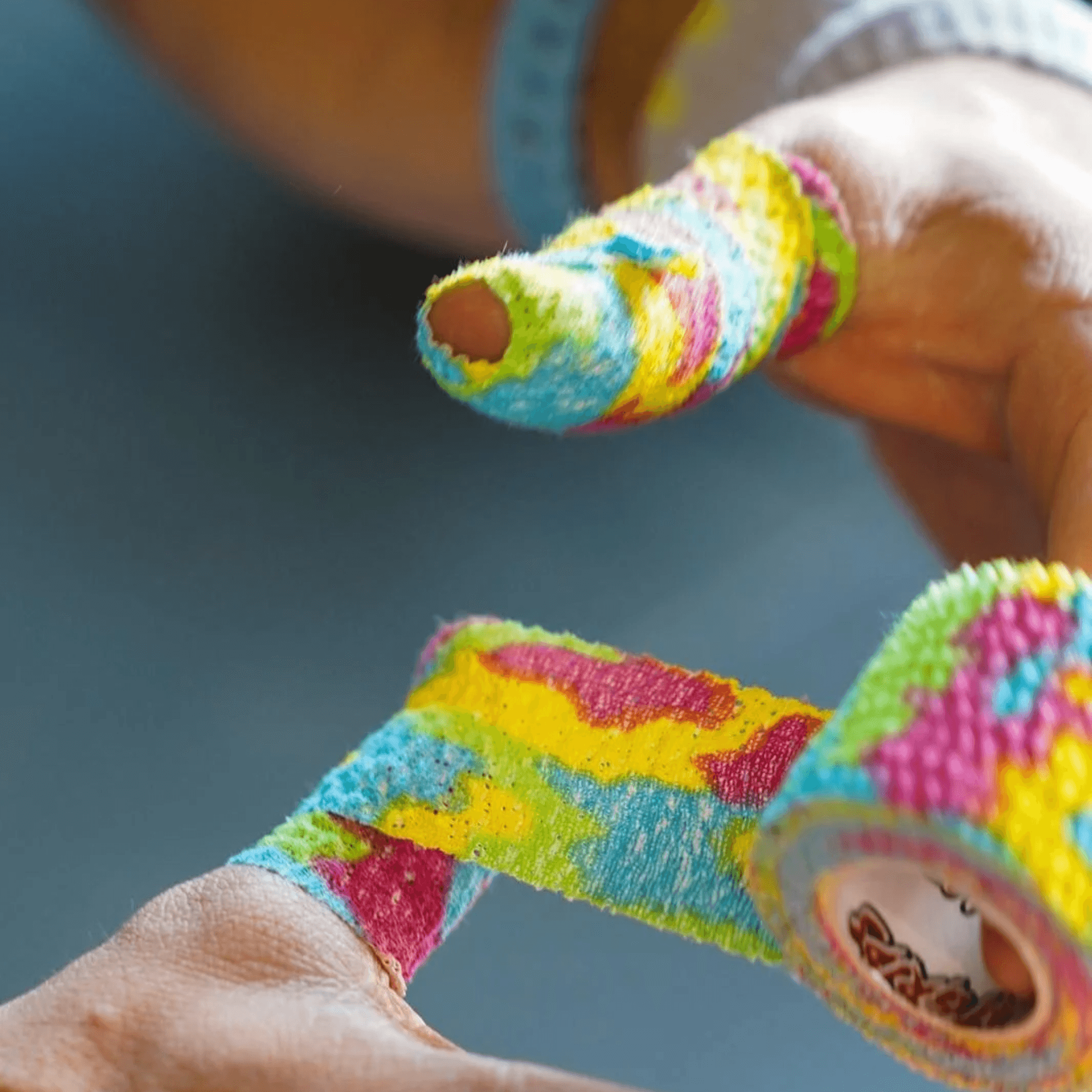 Tape CrossFit CatGrips multicolor envolviendo un pulgar